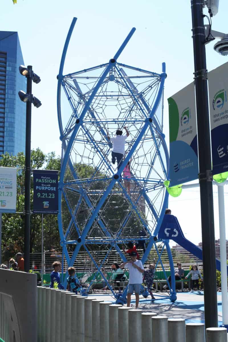 Children play on a blue climbing structure in a park