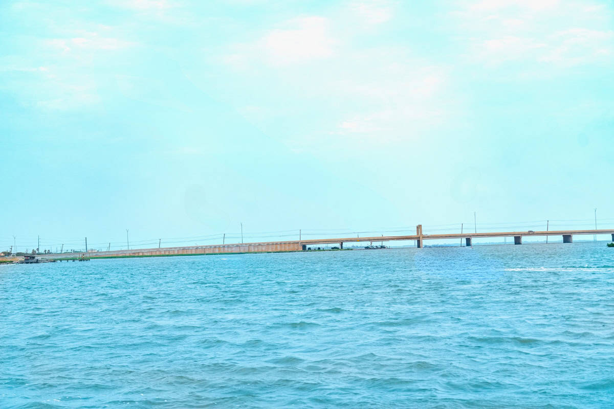 a bridge over water with a boat in the background