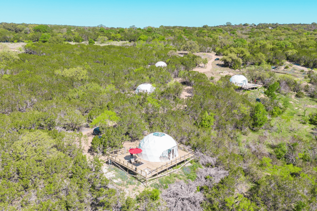 Aerial view of a large dome nestled in a forest, surrounded by lush green trees and nature.