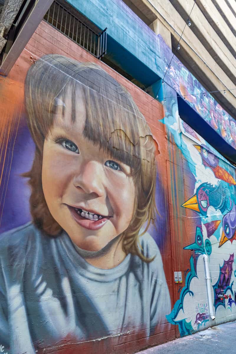 A mural of a smiling child on a building wall.