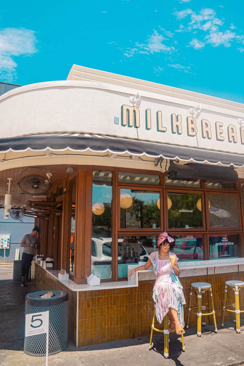 a woman standing outside a milk bread shop