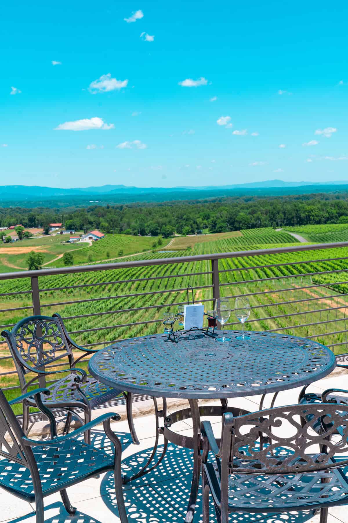 a table and chairs on a balcony overlooking a vineyard