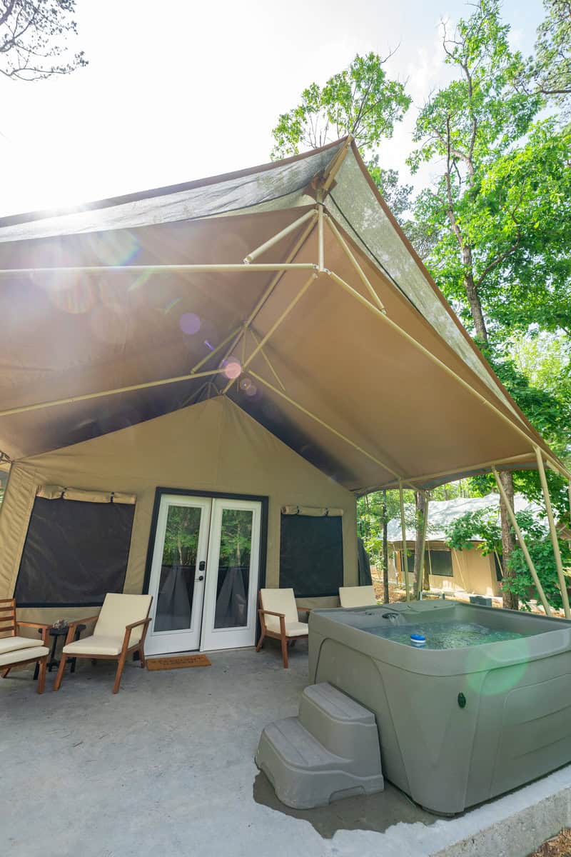 Luxury canvas tent with hot tub in a forest setting.