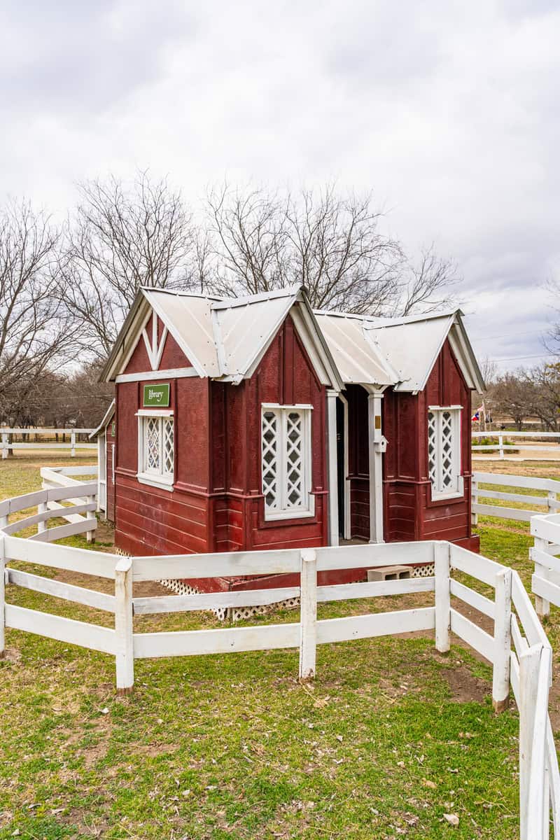 a small red house with a white fence around it