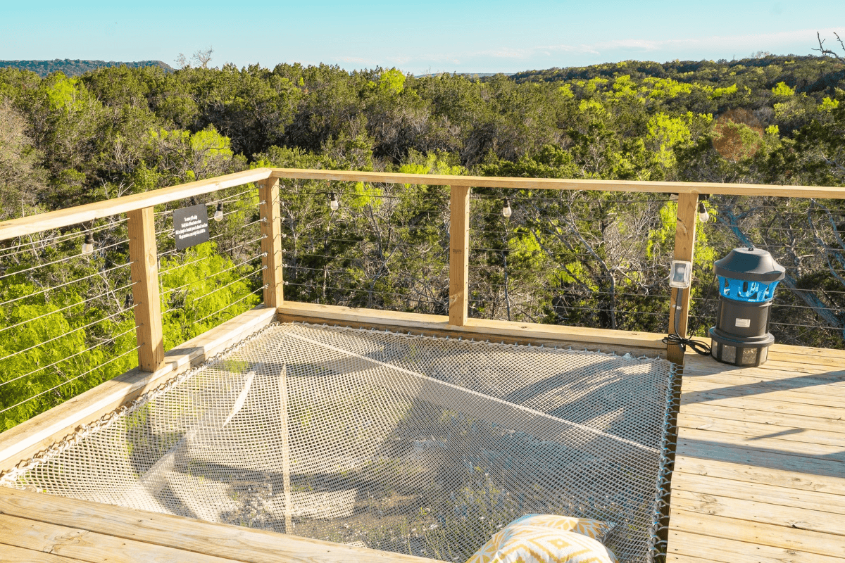 A wooden deck surrounded by lush greenery with hammock