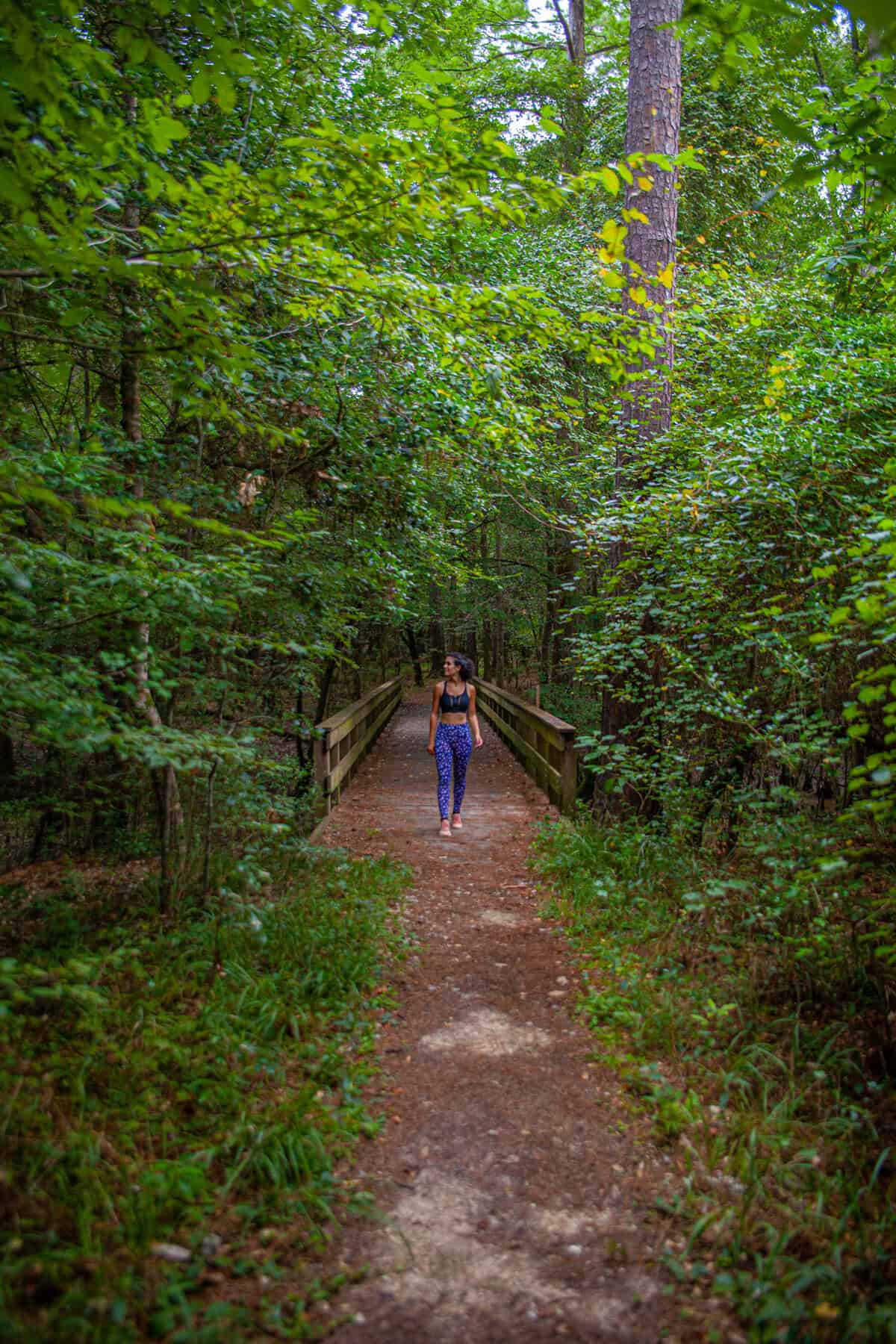 a woman walking on a path through a forest