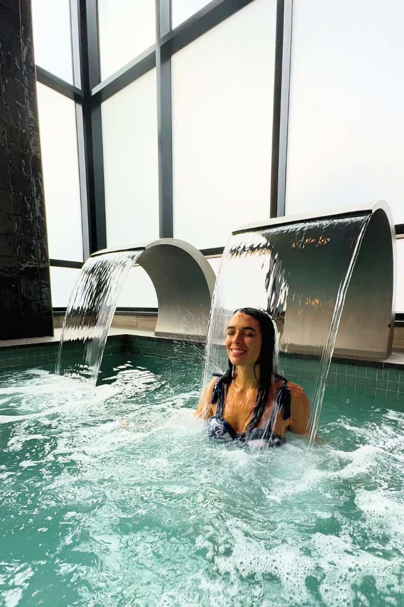 a woman in a pool with water falling from her head