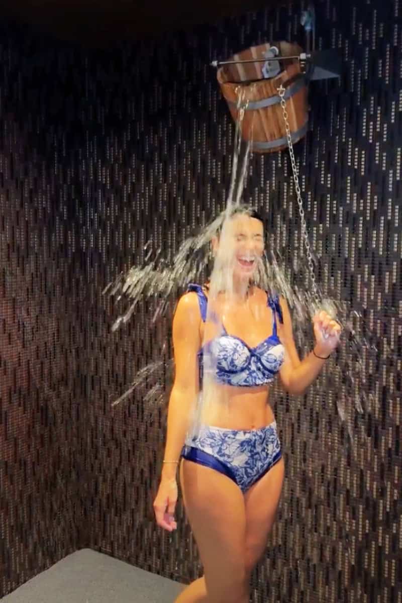 a woman in a bathing suit under a bucket of water