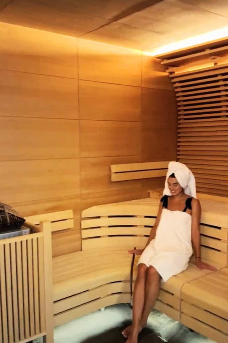 a woman sitting on a wooden bench in a sauna