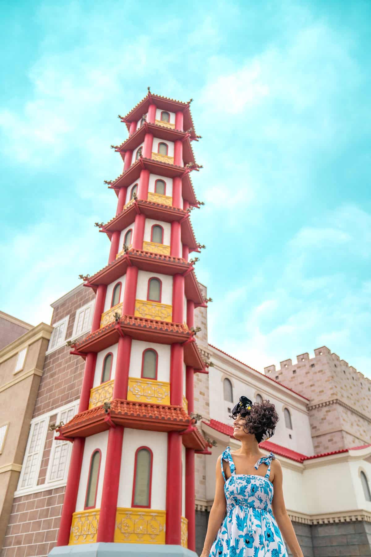 a woman in a blue dress standing in front of a tall building