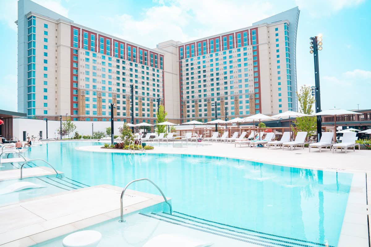 a pool with chairs and umbrellas in front of a large building