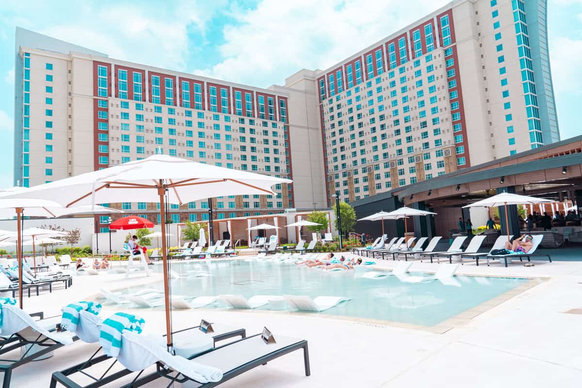 a pool with lounge chairs and umbrellas in front of a large building