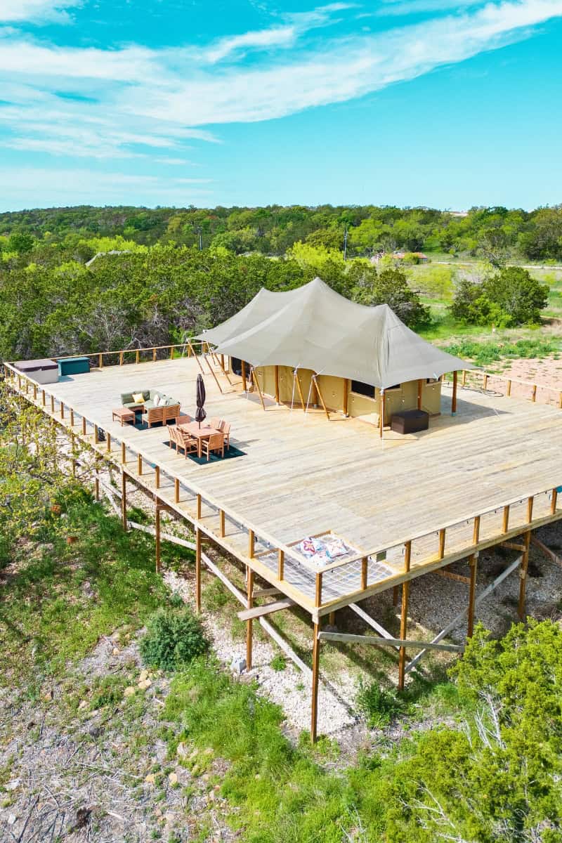 a tent on a deck surrounded by trees