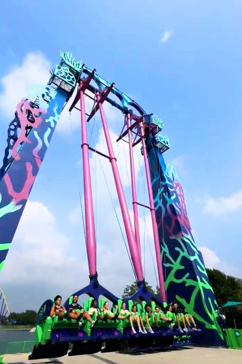 Colorful swing ride with people in green at an amusement park.