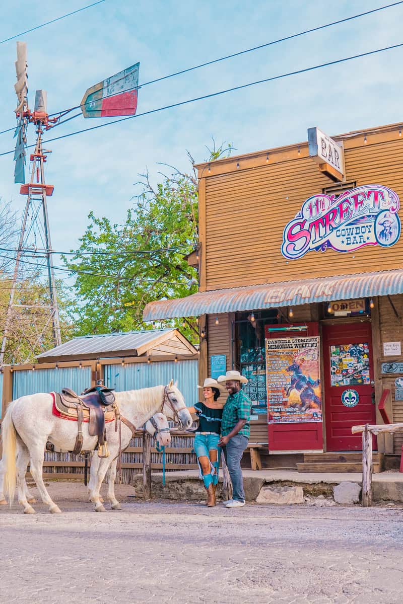 Two people and a horse in front of the "11th Street Cowboy Bar."