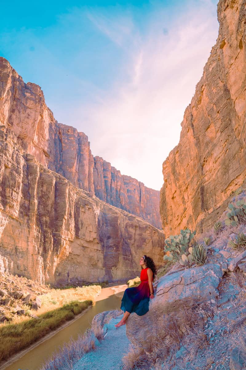 Person sitting on a rocky ledge overlooking a canyon.