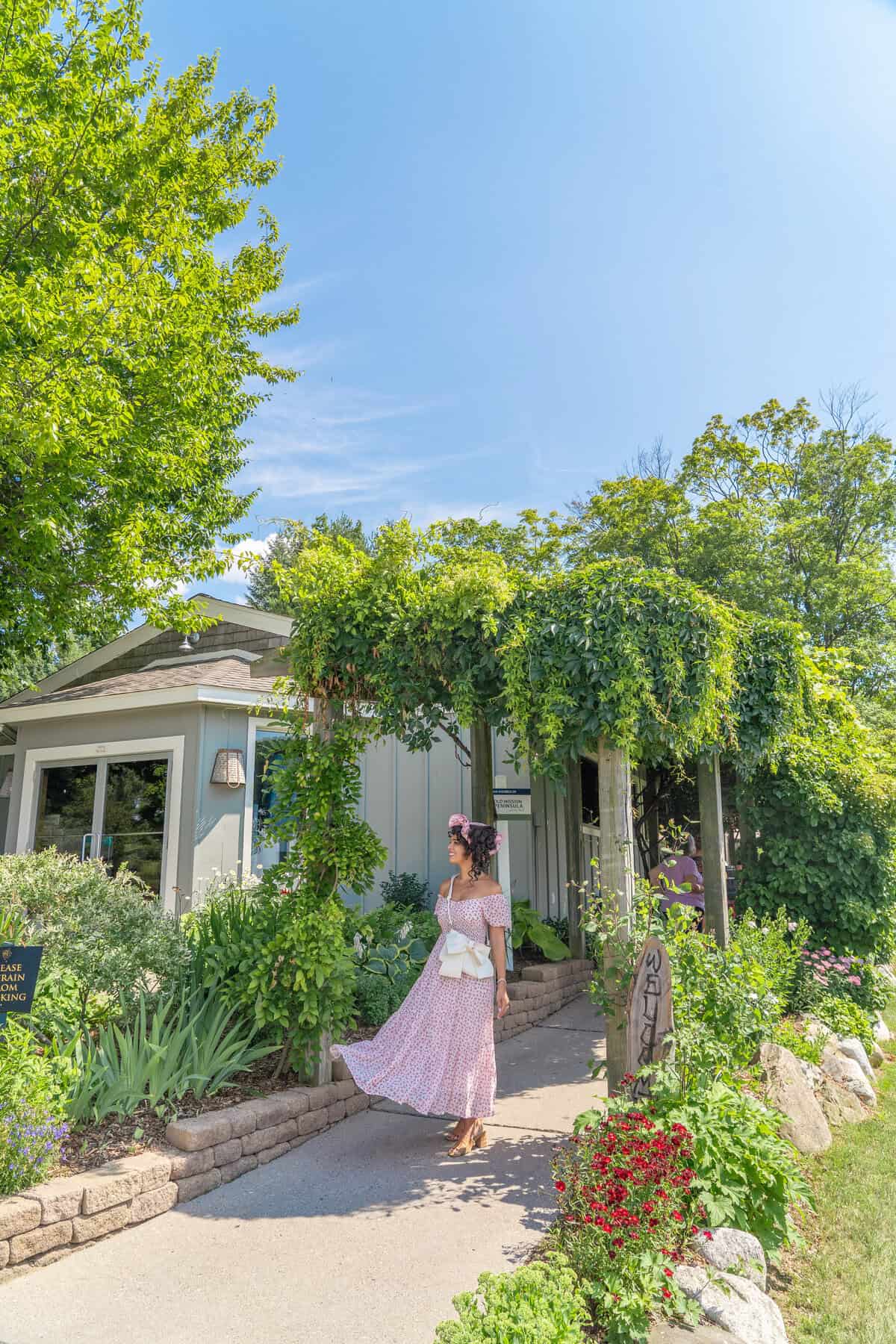 Person in a floral dress walking by a lush garden 