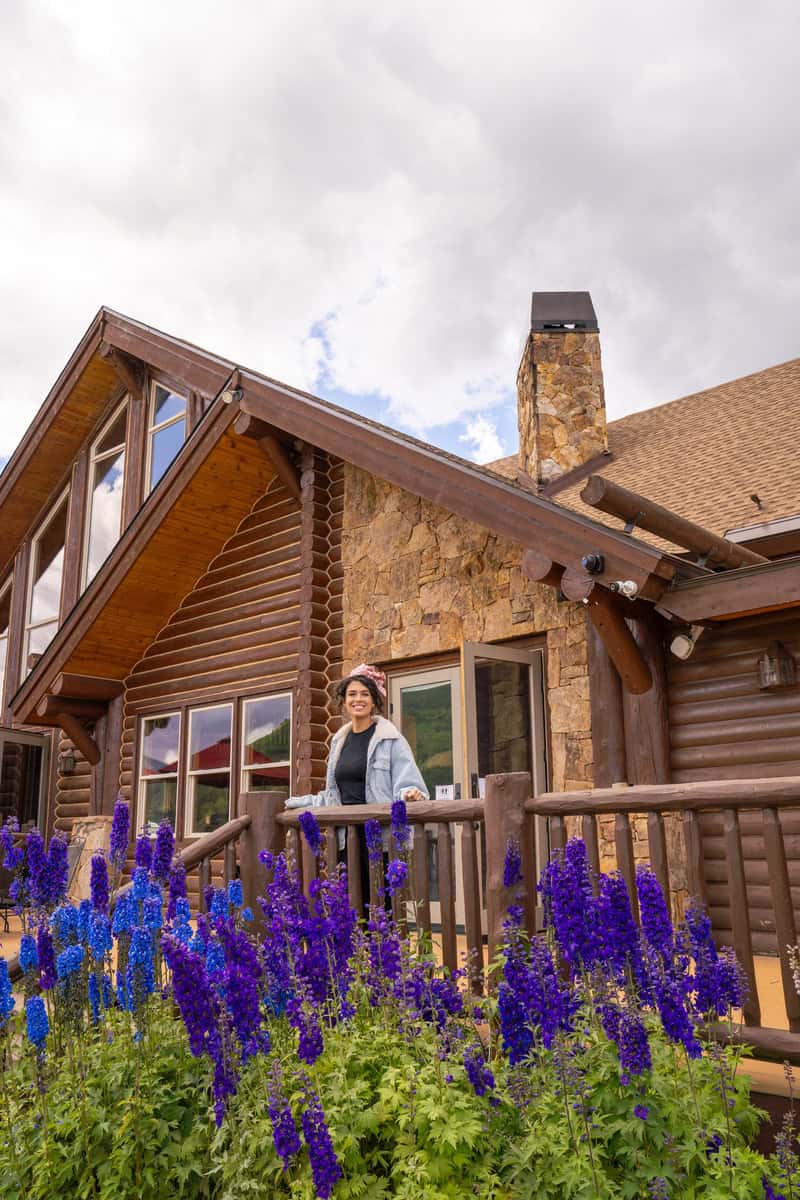 Person standing on a deck by a log cabin