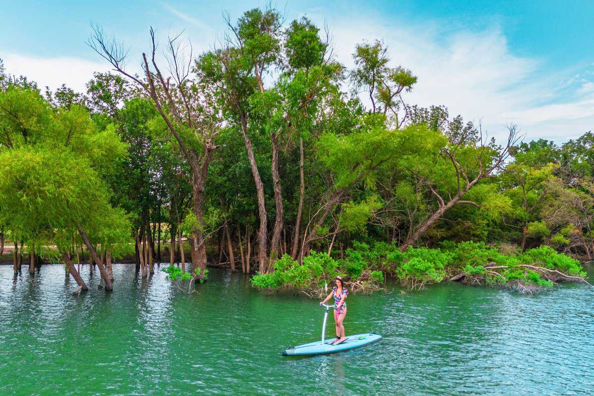 Woman paddleboarding on a tranquil green lake