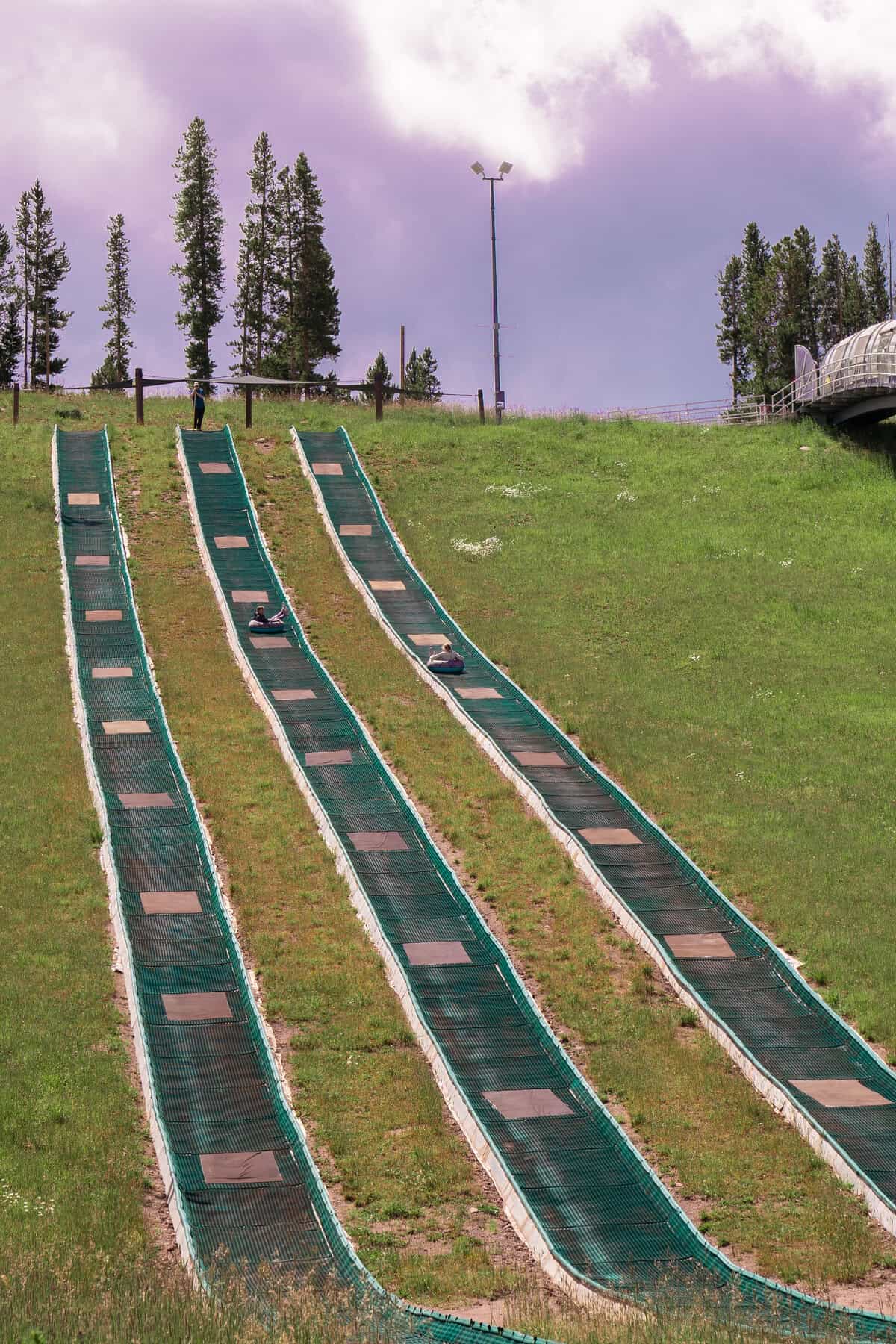 Three parallel summer toboggan tracks on a grassy hillside