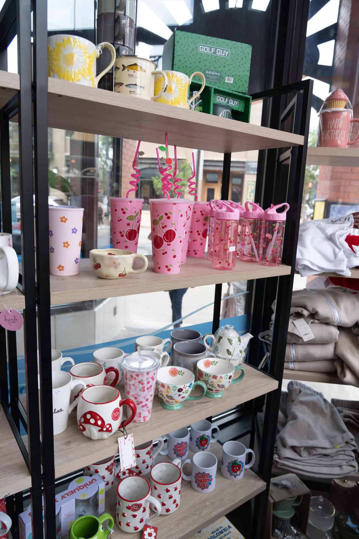 A variety of colorful mugs and cups on shelves in a gift shop.