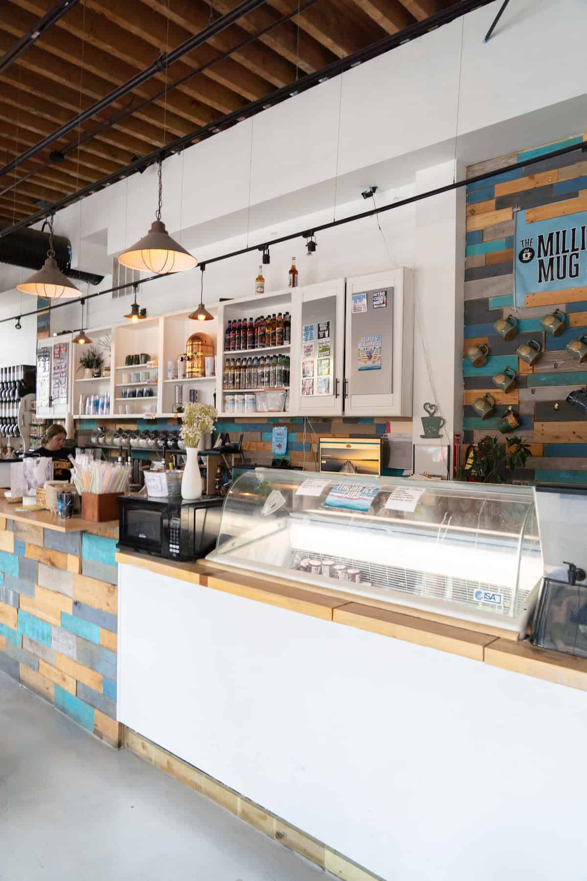 Interior of a cafe with a display counter, shelves with bottles, and pendant lights.