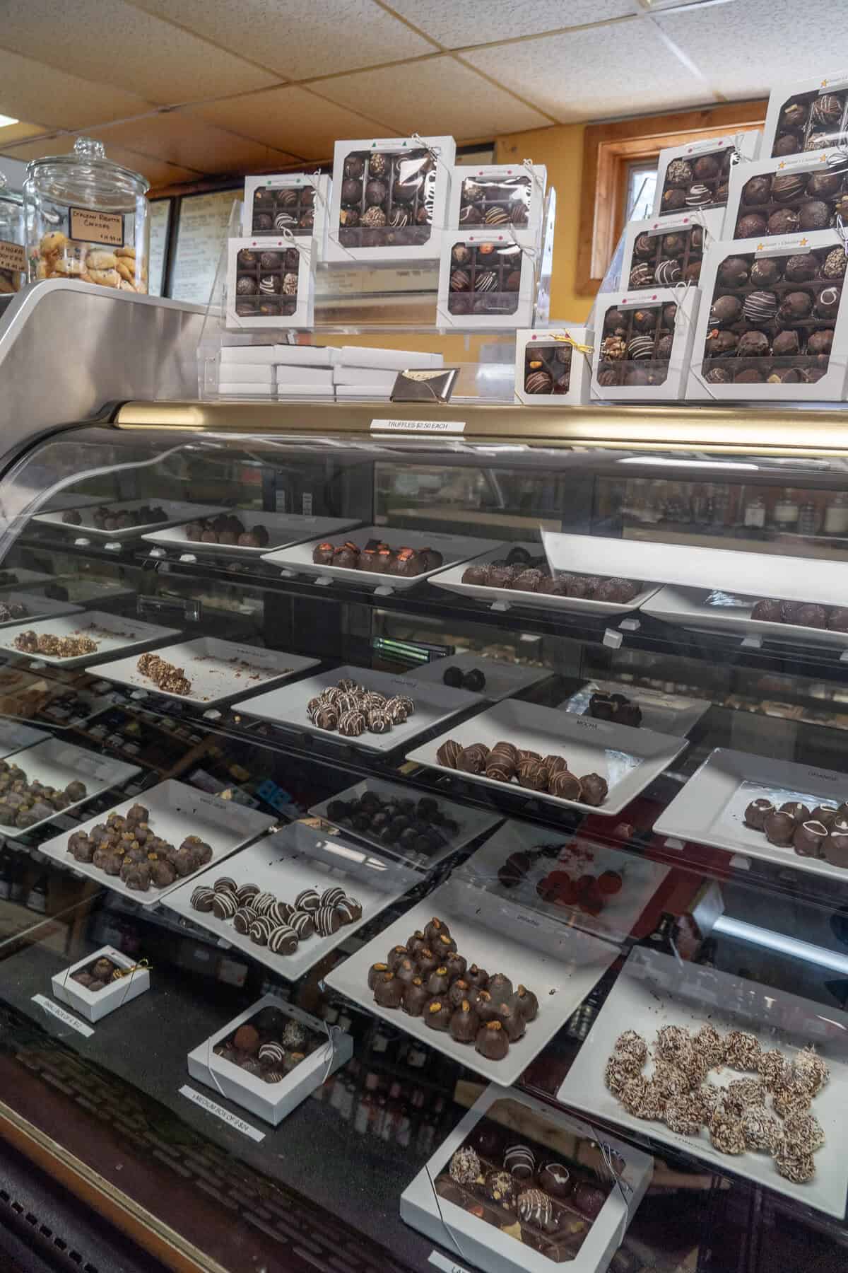 Assorted chocolates displayed in a glass case at a confectionery shop.