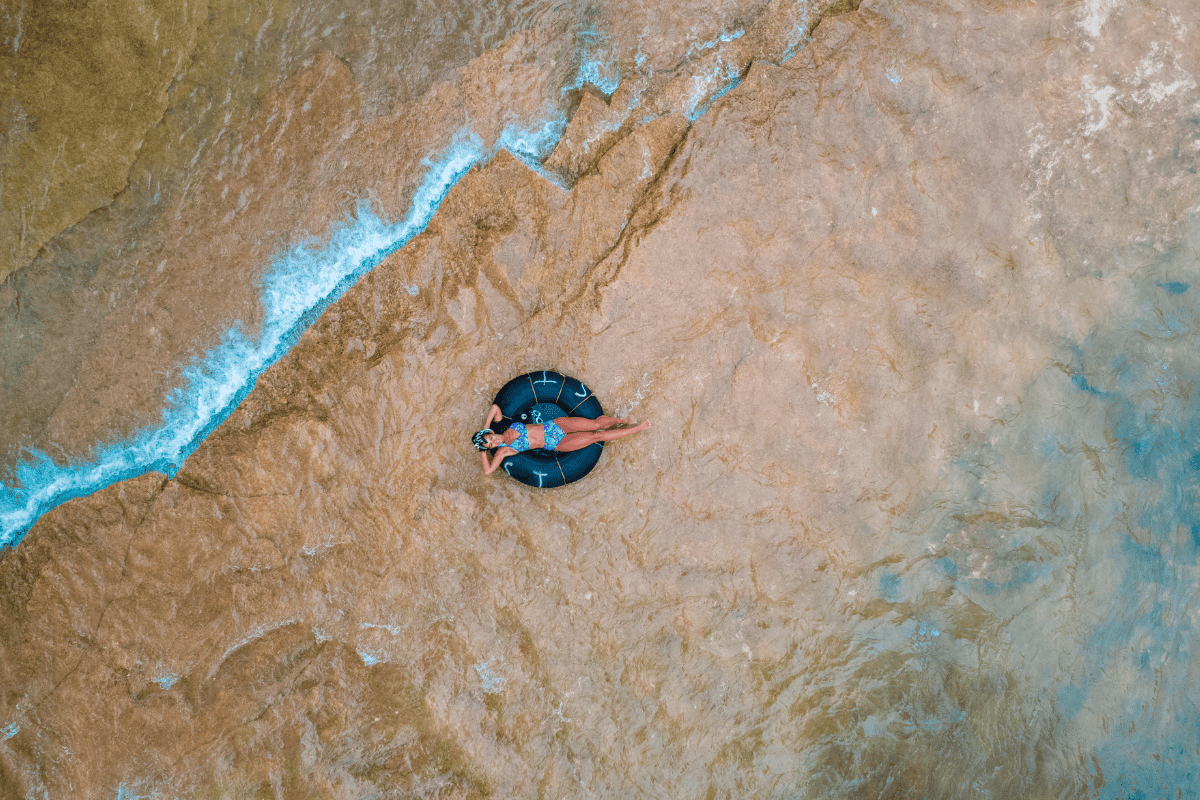 Person on an inner tube in a river, aerial view.