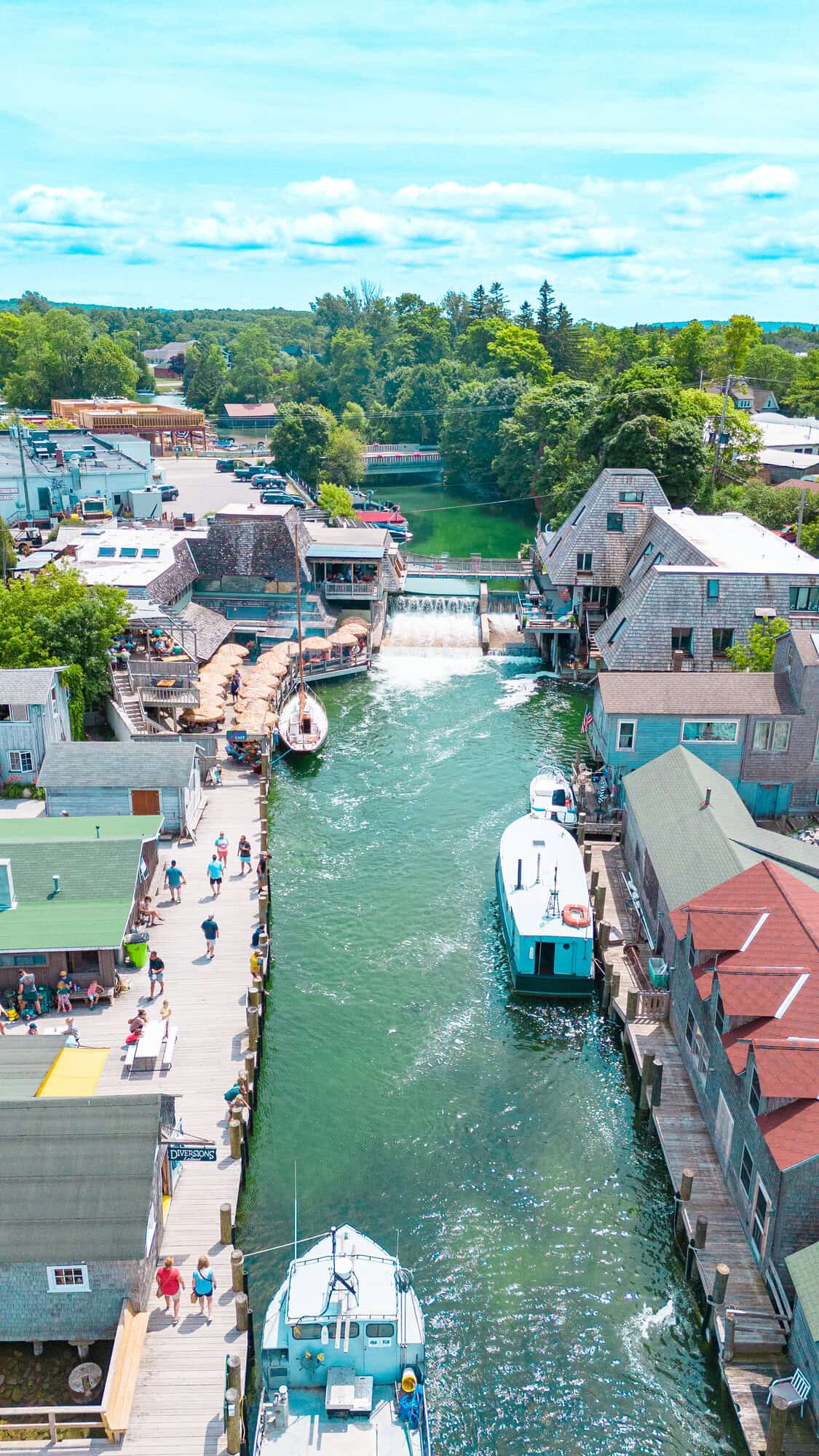 Aerial view of a vibrant waterfront with boats, buildings, and people on the docks.