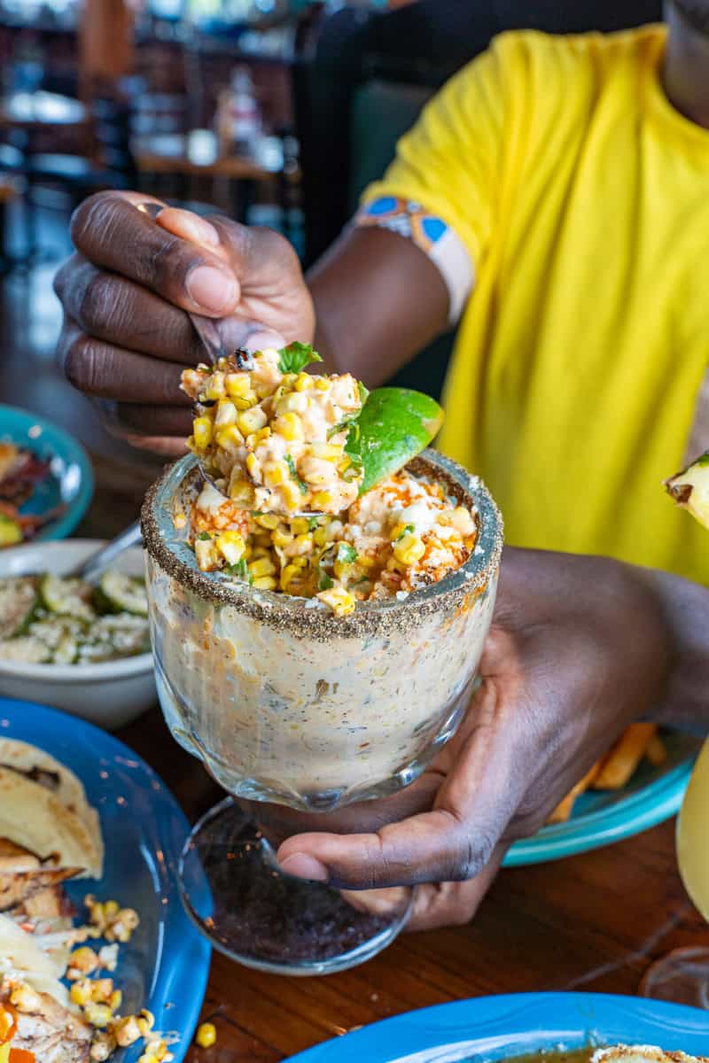 Person holding a glass of elote garnished