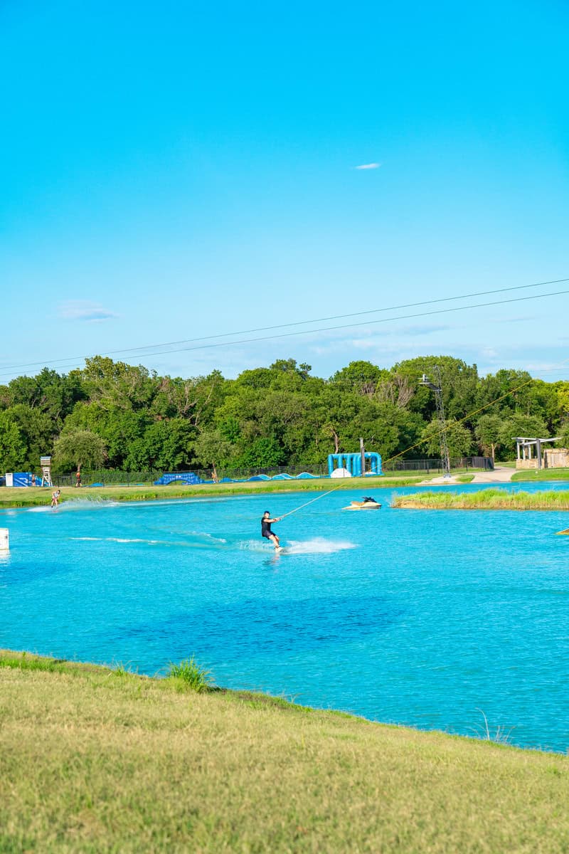 A person wakeboarding on a bright blue lake