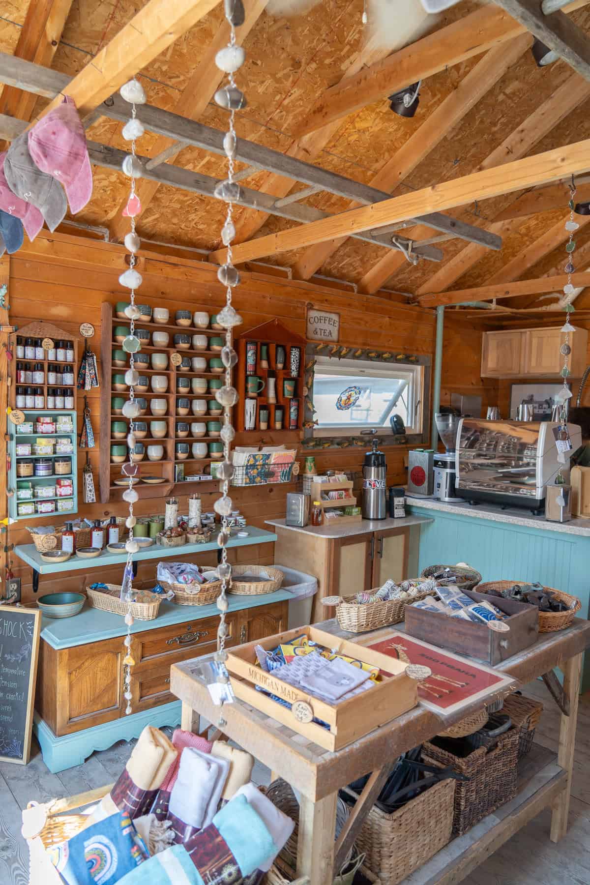 Cozy rustic shop interior with shelves of mugs, coffee equipment, and assorted goods.