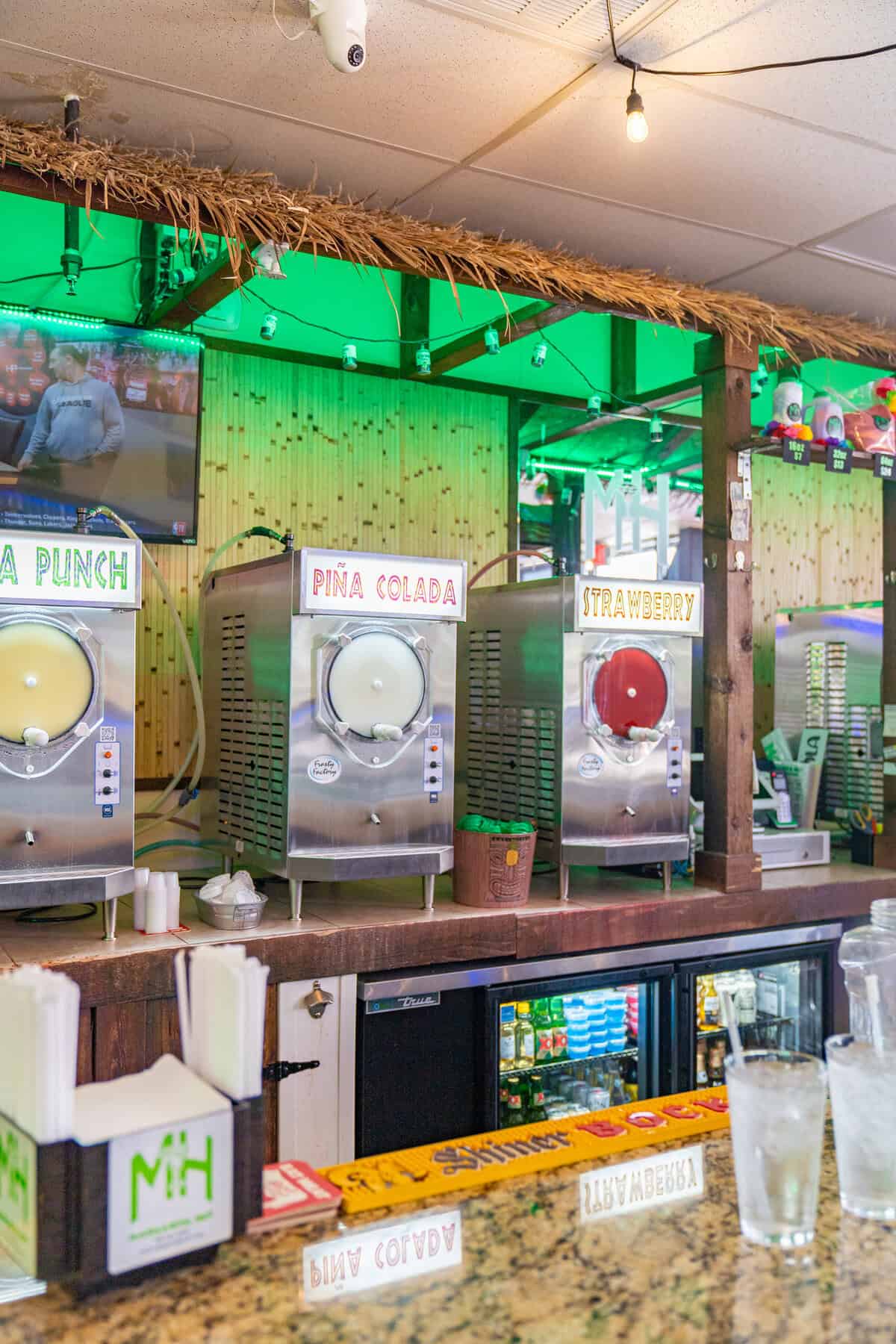 A tropical bar with three frozen drink machines