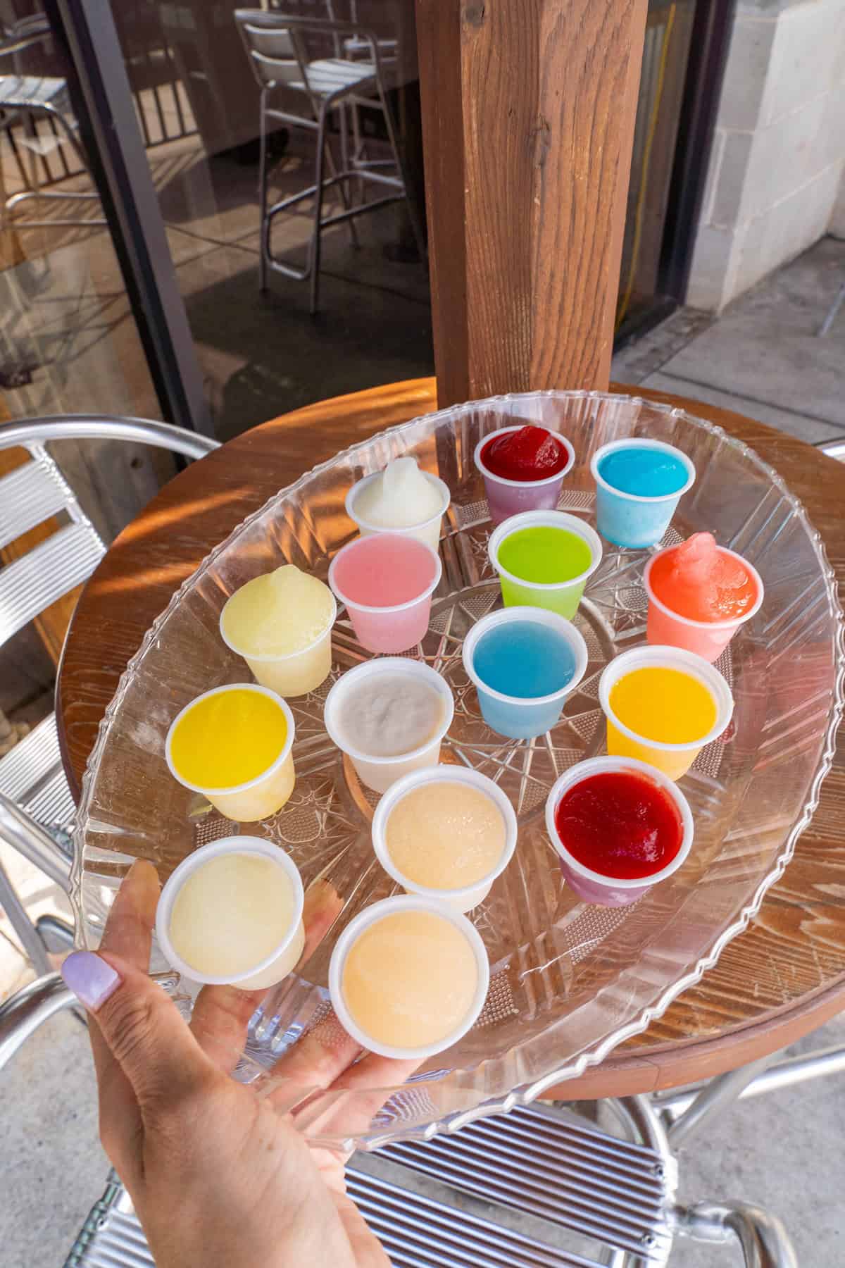 A person holding a clear tray filled with colorful sauce cups.