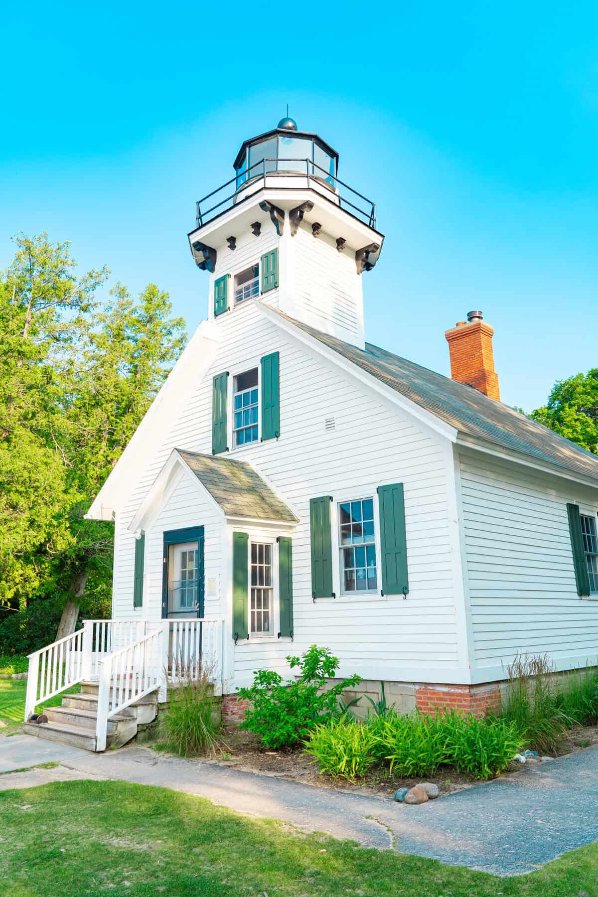 A quaint white lighthouse with green shutters