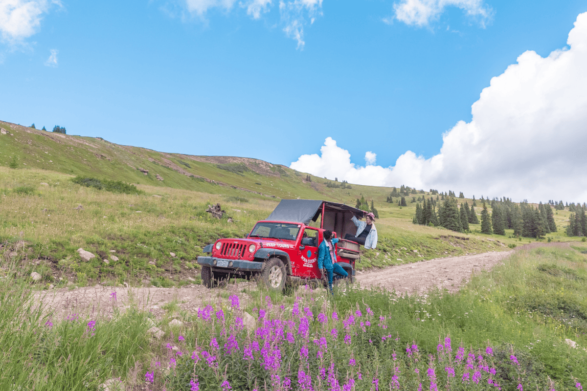 Red jeep with open trunk on a dirt road