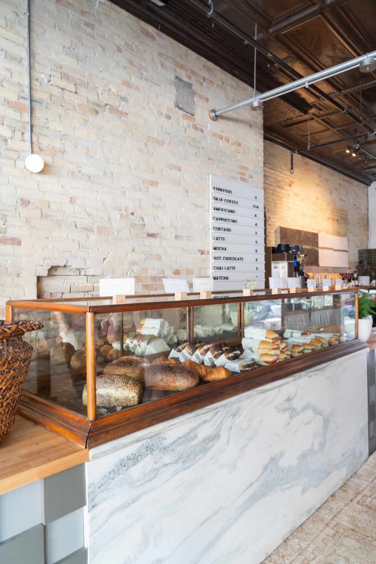 Modern bakery interior with assorted breads on display and a menu board.