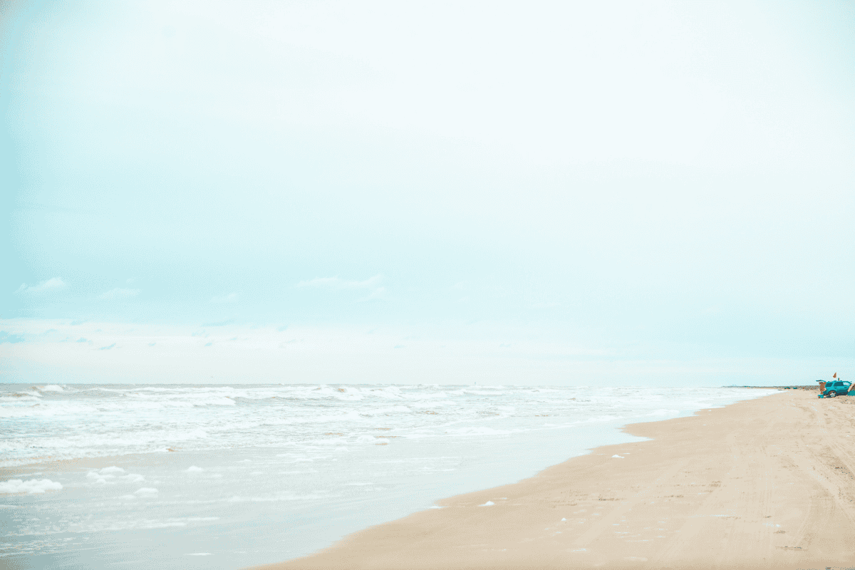 A tranquil beach scene with gentle waves, soft sand, and a clear sky.