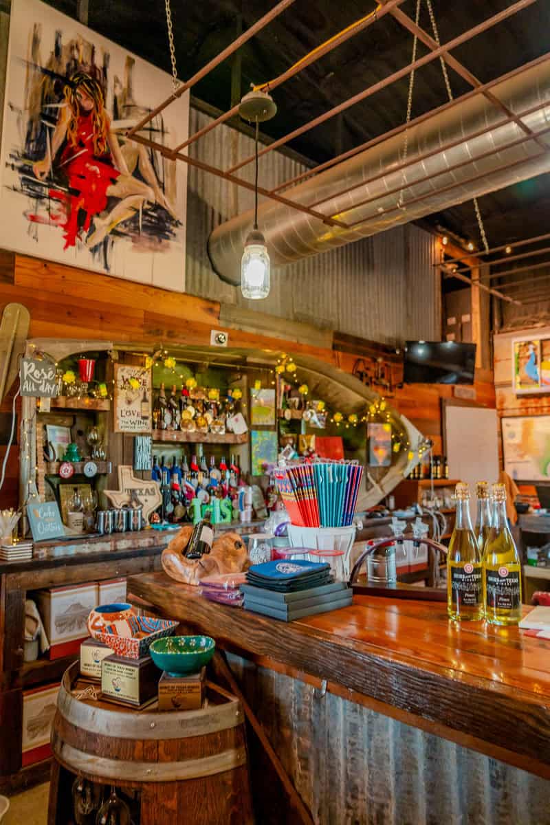 A cozy bar interior with eclectic decor, colorful straws, and hanging lights.