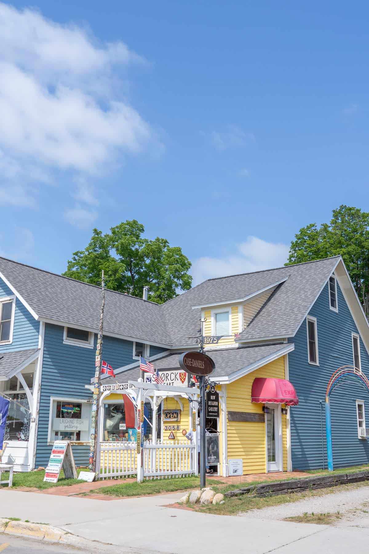 Colorful storefronts under a blue sky with light clouds.