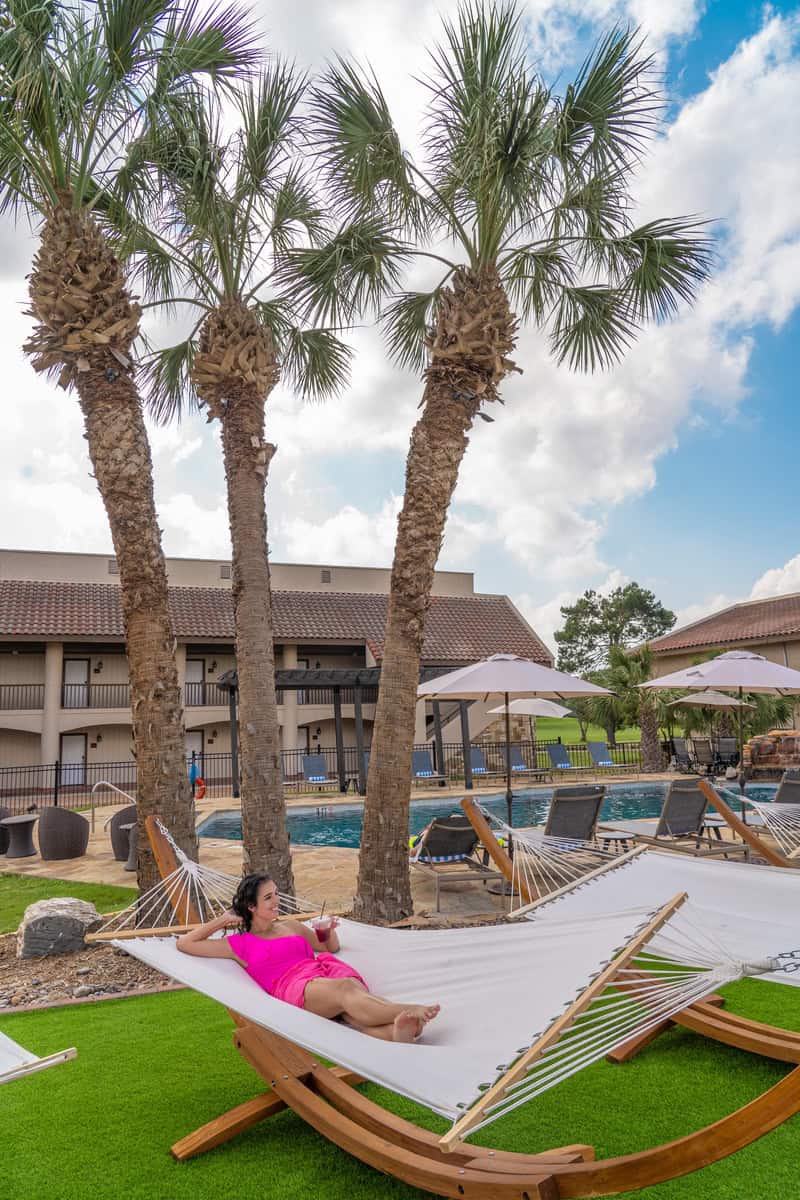 Person relaxing on a hammock beside a pool