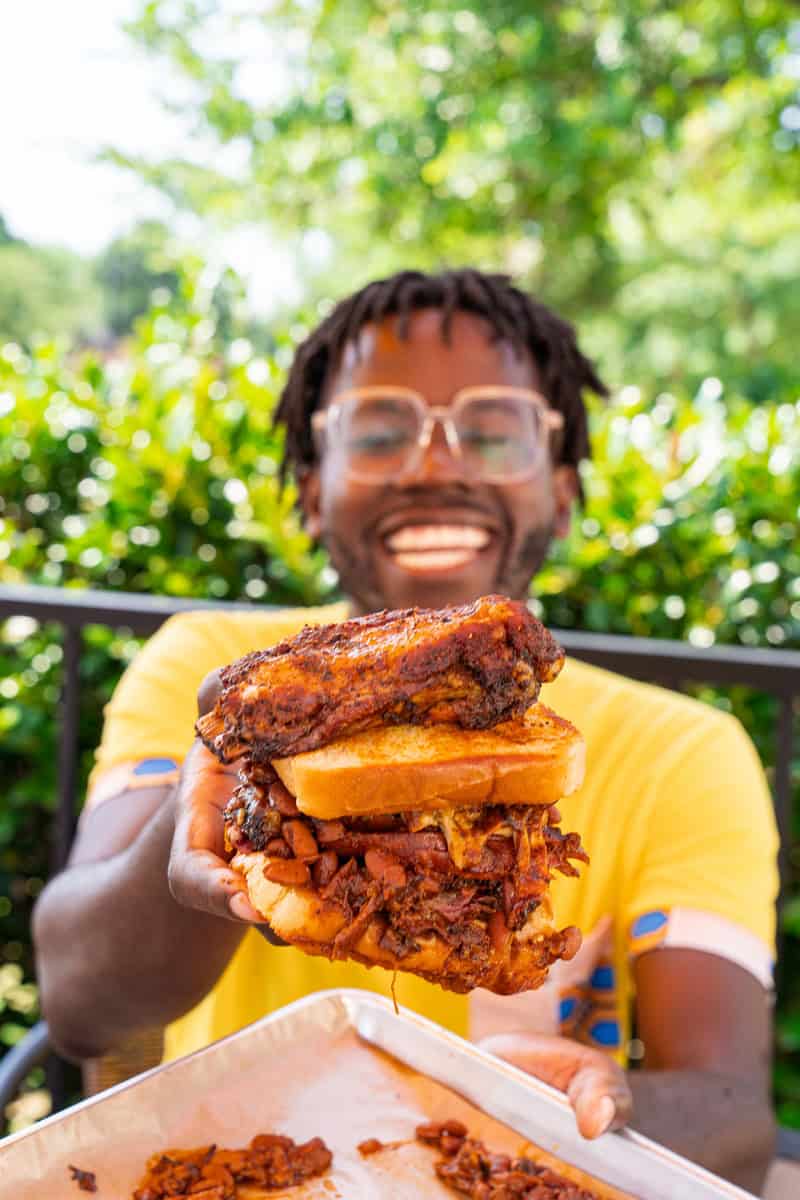 A person holding a towering barbecue sandwich