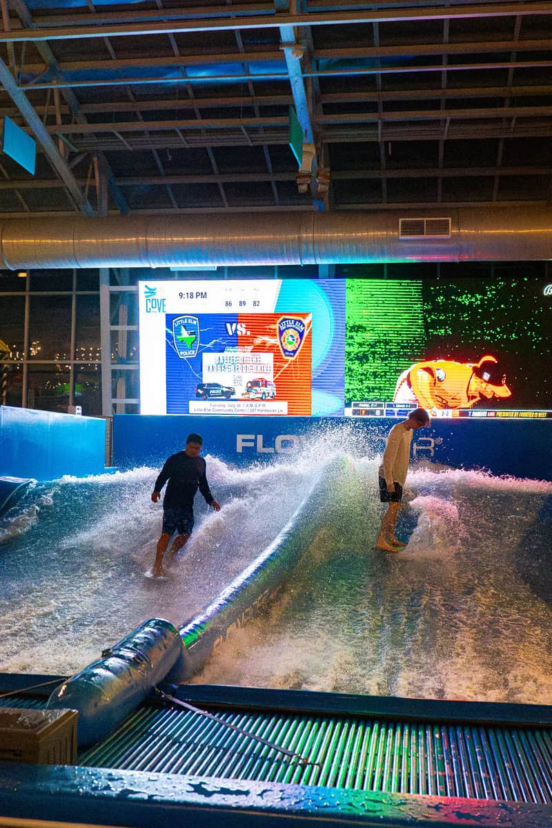 Indoor flowboarding with two individuals on artificial waves