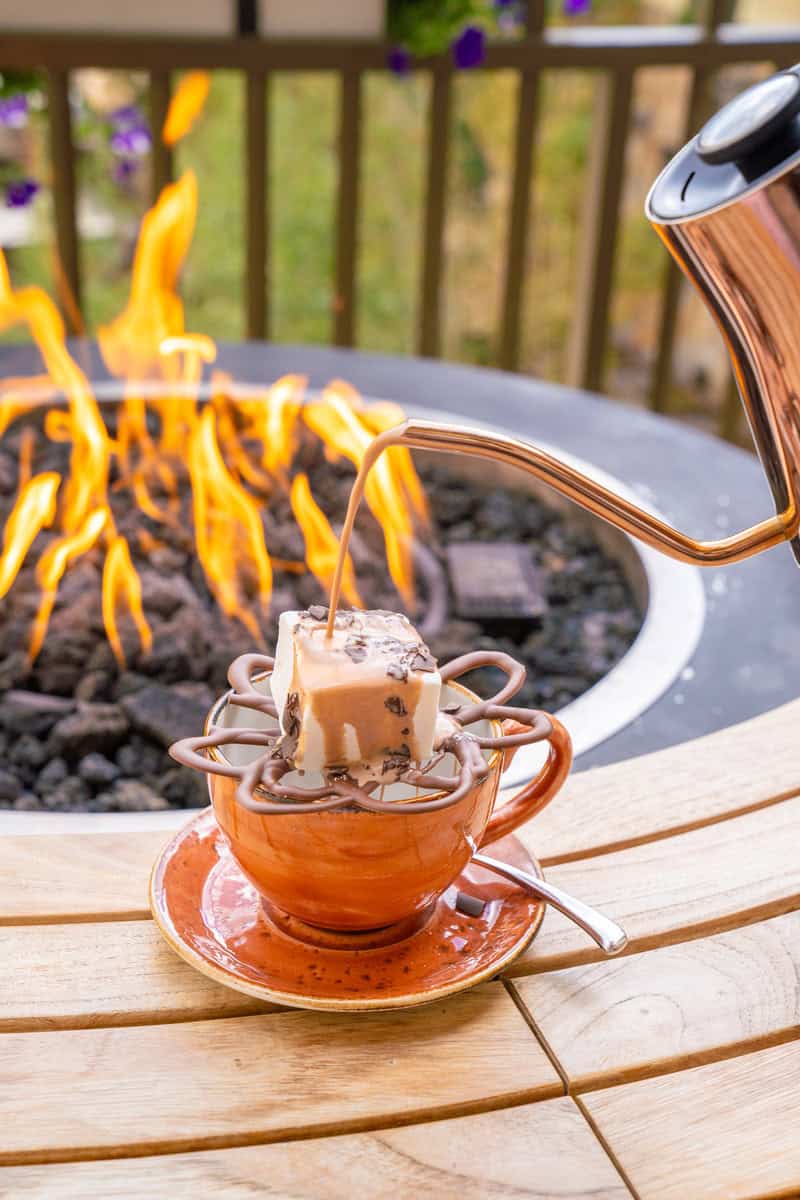 Melting a cube of hot chocolate on a stand over a cup