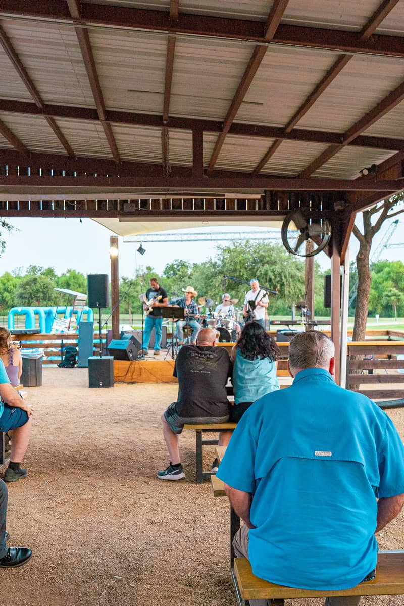 People watching a live band perform in a park pavilion.