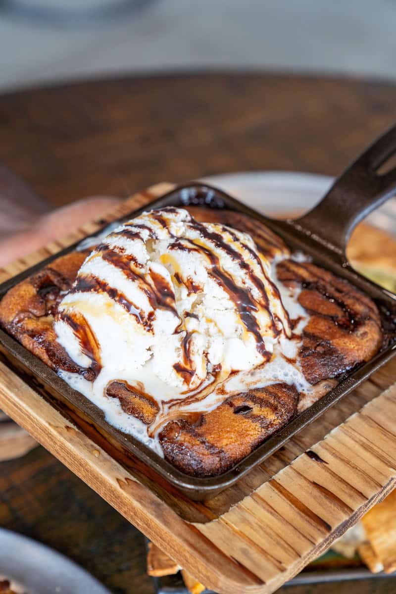 A skillet cookie with a scoop of ice cream and chocolate syrup drizzle.