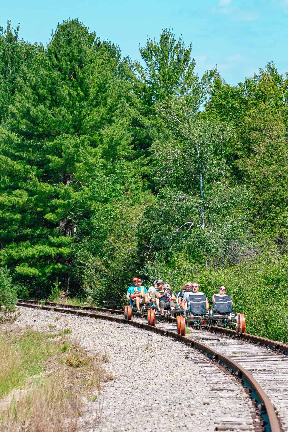 Rail bikes on tracks surrounded by lush greenery.