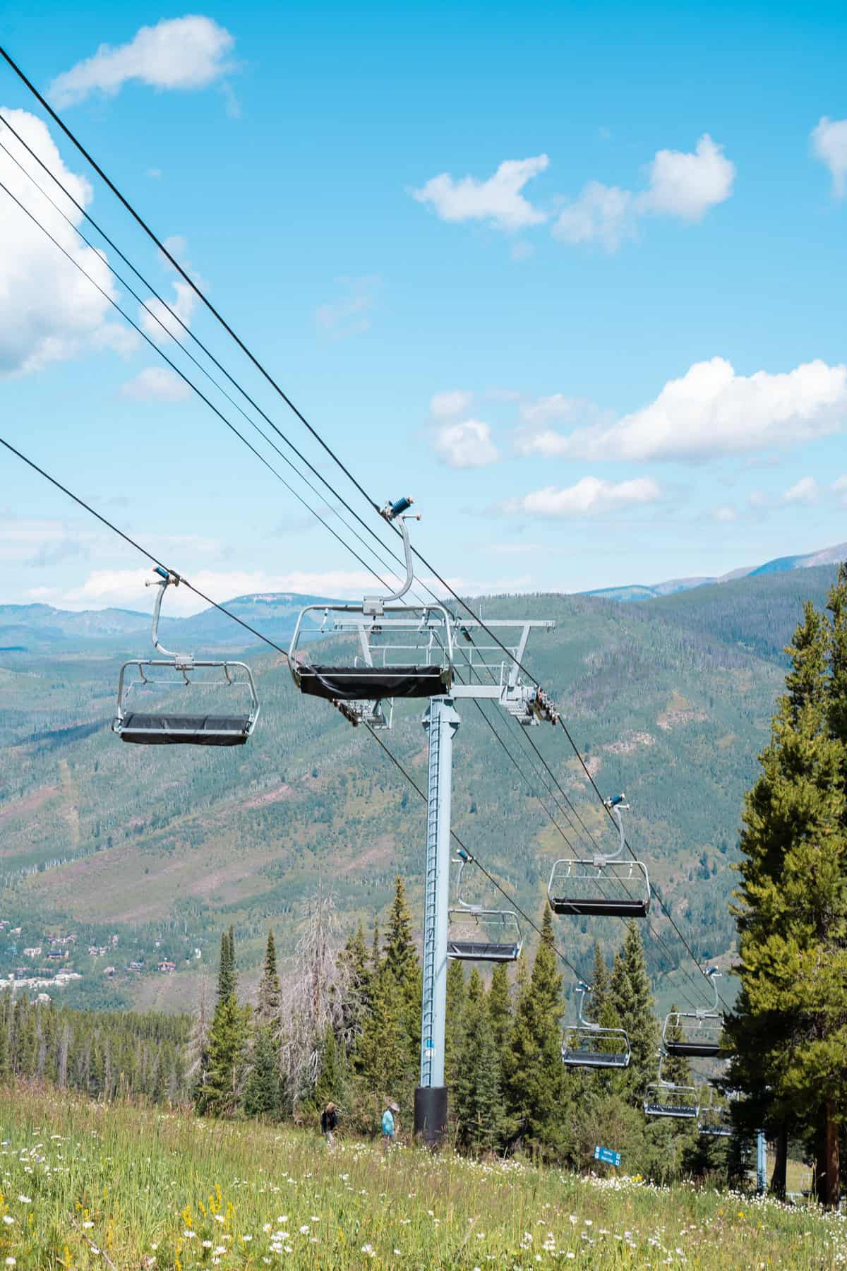 Empty ski lift chairs over a green mountainside