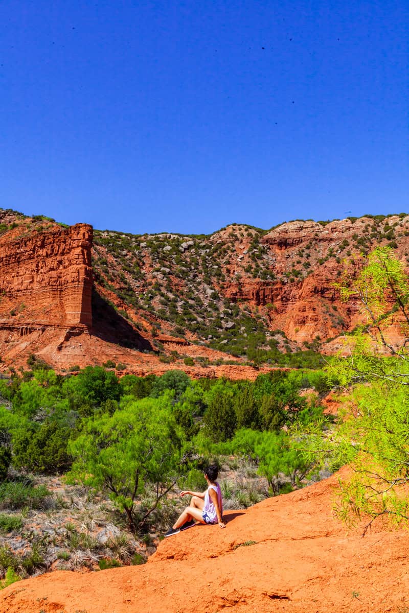 Person sitting on red earth trail