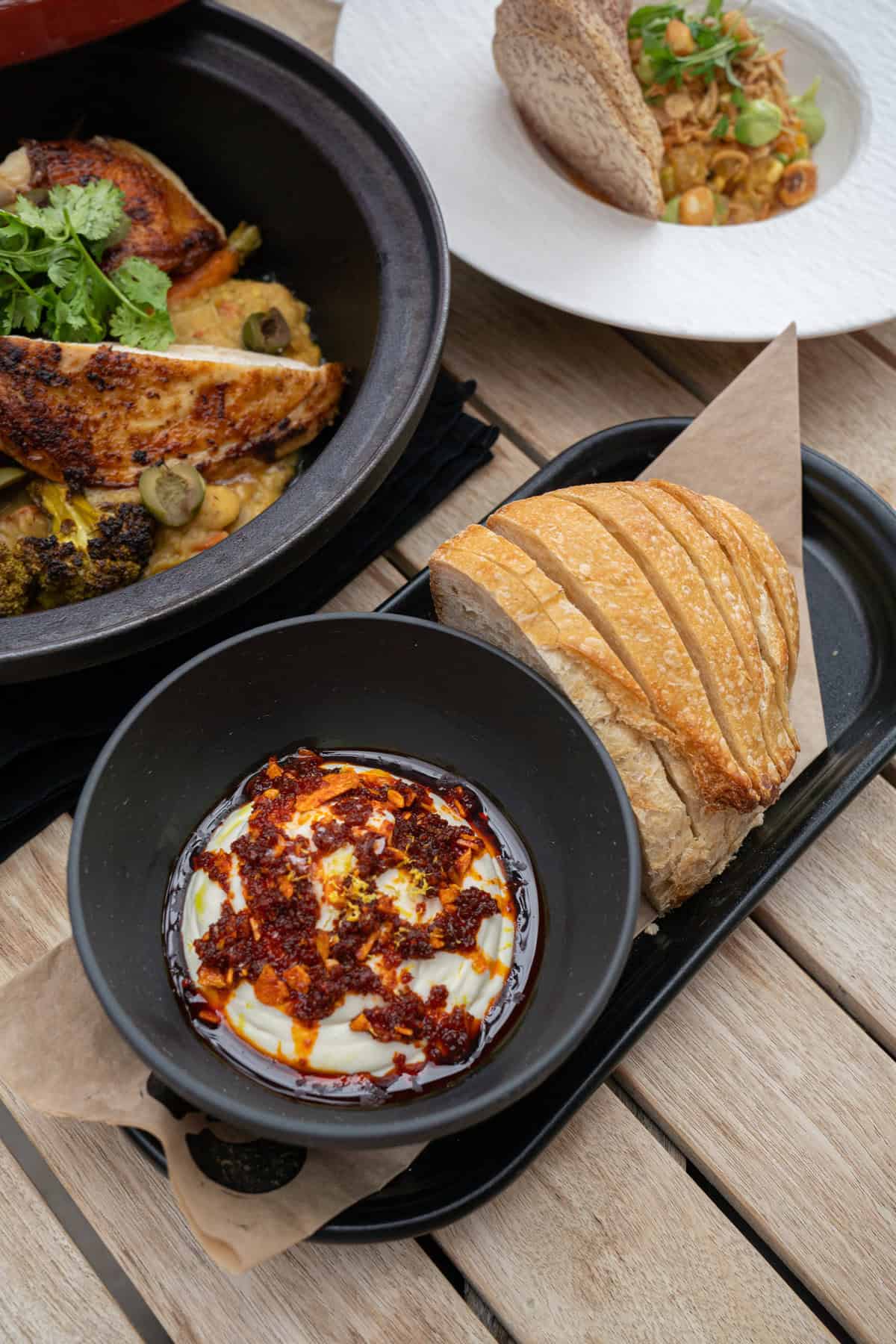 Grilled chicken in a pot, yogurt with chili, and sliced bread